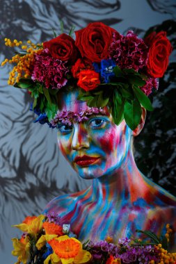 Yüzü çiçek çelenginde renkli boyalarla boyanmış bir kızın portresi. Frida Kahlo 'nun izinden.