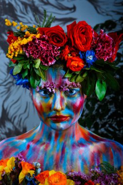 Yüzü çiçek çelenginde renkli boyalarla boyanmış bir kızın portresi. Frida Kahlo 'nun izinden.