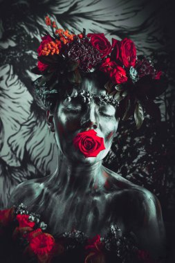 Yüzü çiçek çelenginde renkli boyalarla boyanmış bir kızın portresi. Frida Kahlo 'nun izinden.