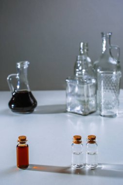 Büyük bir sürahi ve koyu sıvı bir test tüpü sürahinin yanında durur ve hafif sıvı ile test tüpleri.