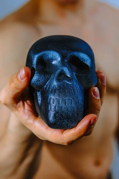 artificial skull in the hand of a strong man