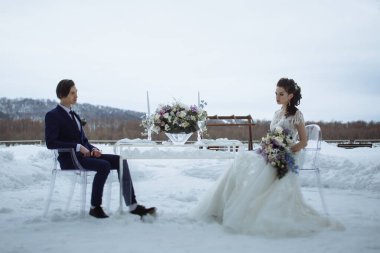 Gelin ve damat caddedeki cam bir masada oturuyorlar. Kış, etrafta kar