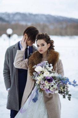 Güzel bir buketi olan gelin ve düğün kışı çekimlerinde damat.