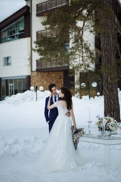 冬の舞台結婚式の写真 ガラスのテーブルと椅子の横に美しい花束と新郎新婦 — ストック写真