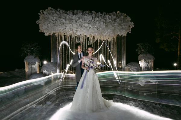 Bruidegom Omarmt Bruid Met Geschilderde Vleugels Achtergrond Van Bruiloft Winterversieringen — Stockfoto
