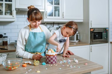 Aşçı ve kızı, Paskalya pastasının üzerine tatlı figürler sererler.