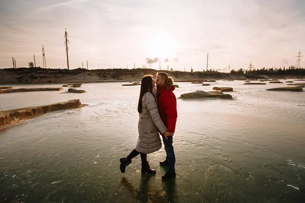 ダウンジャケットの恋人砂のピットの氷の上を歩く — ストック写真