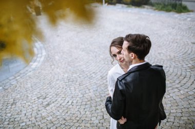 Aşıklar, sarı yapraklı bir ağacın altında birbirlerine sarılıyorlar.