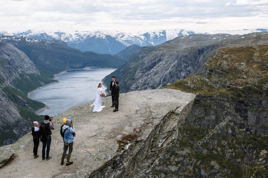 Photographers and videographers filming an off-site wedding ceremony on a rock fragment in Norway called the Troll's tongue