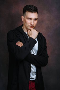 Siyah ceketli, beyaz tişörtlü, kırmızı kotlu bir gencin portresi.