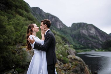 Nehrin arka planında bir kayanın üzerinde duran düğün çifti.