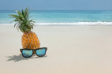 Turkuaz Karayip deniz suyuna karşı güneş gözlüklü ananas meyvesi. Tropik yaz tatili konsepti