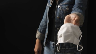 Elinde toz maskesi olan bir kadın, 2.5 yaşında siyah bir arka planda. 2020 Corona virüs krizinde insanları yüz maskesi kullanarak virüs enfeksiyonundan koruyorlar.