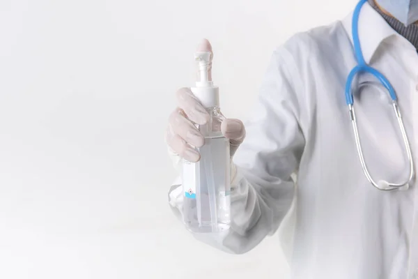 Doktor elleri, beyaz arka planda izole edilmiş alkol dezenfektanı ile yıkama elini kullanıyor. 2020 Corona virüs krizinde insanları yüz maskesi kullanarak virüs enfeksiyonundan koruyorlar.