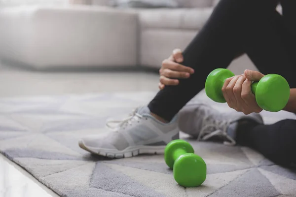 Spor giyim sektöründe sportif bir kadın dambıllarıyla yerde oturuyor. Spor ve eğlence konsepti. Coronavirus önleme kampanyası için evinizde kalın.
