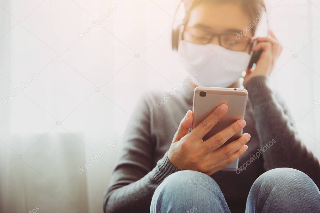 Young woman wearing face mask listening to music at home. People infected with coronavirus disease in the couch at home. Stay home. Pandemic virus disease covid 19. Health concept.