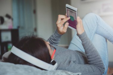 Evdeki oturma odasında dinlenirken akıllı telefon kullanan ve online alışveriş yapan genç bir kadın. Çevrimiçi alışveriş ve modern yaşam tarzı kavramı. Boşluğu kopyala