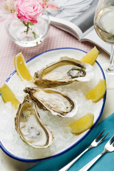 Open wet oysters on a plate with lemon and oysters knife with wi