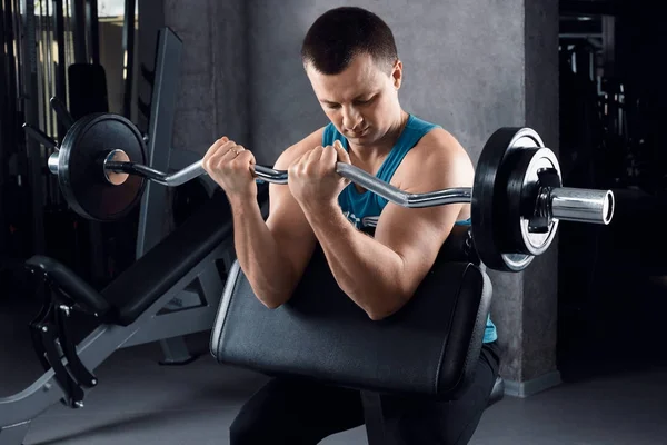 Hombre atlético bombeando músculos con mancuernas —  Fotos de Stock