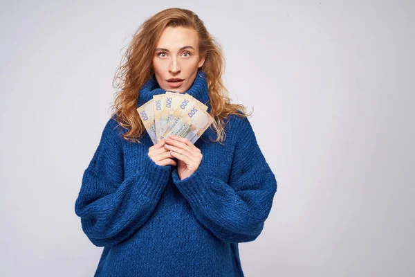 Девушка в свитере удивлена деньгами, на сером бэкгре — стоковое фото
