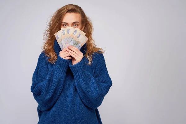 A cheerful woman in a sweater, covers part of the face with mone — Stock Photo, Image