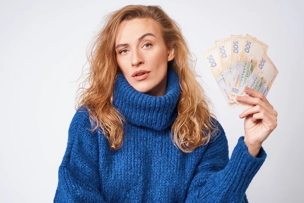 Девушка в свитере удивлена деньгами, на сером бэкгре — стоковое фото