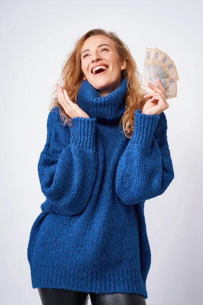 Joyful woman in a sweater, happy with money hryvnia holding them — Stock Photo, Image