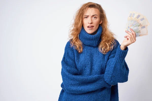 Young woman in a sweater is surprised by money, on a gray backgr — Stock Photo, Image