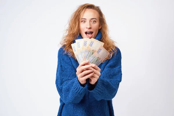 Радостная женщина в свитере, счастливая с деньгами гривны, держа их — стоковое фото