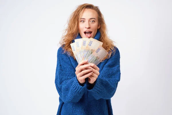 Joyful woman in a sweater, happy with money hryvnia holding them — Stock Photo, Image