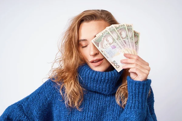 A cheerful woman in a sweater, covers part of the face with mone — Stock Photo, Image