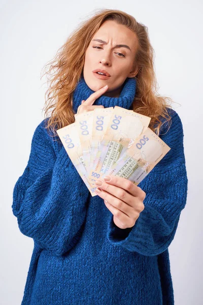 Young woman in a sweater is surprised by money, on a gray backgr — Stock Photo, Image