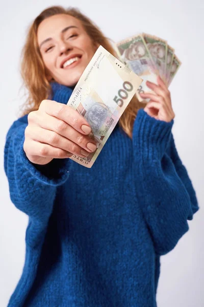 Joyful woman sharing money hryvnia holding them in hands on a gr — Stock Photo, Image