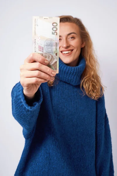 Joyful woman sharing money hryvnia holding them in hands on a gr — Stock Photo, Image