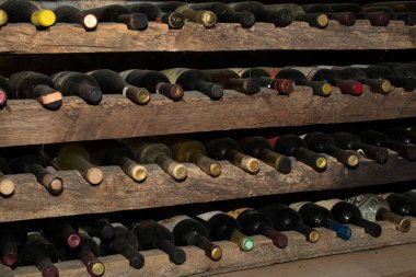 Şarap mahzenindeki bir rafta tozlu eski şarap şişeleri