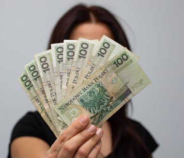 PLN 100 Polonya parası değerindeki bir banknotun kapanışı. Gri arka plandaki bir kadının elinde zloti.