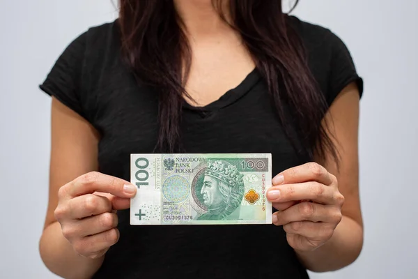 PLN 100 Polonya parası değerindeki bir banknotun kapanışı. Gri arka plandaki bir kadının elinde zloti.