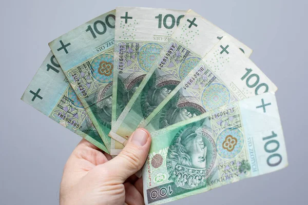 拉近一张面值100波兰兹罗提的钞票 钱的面值是100波兰兹罗提 握在一个灰色背景的妇女手里 — 图库照片