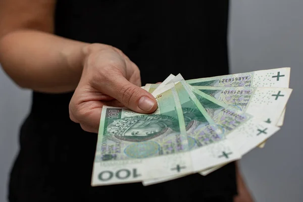 PLN 100 Polonya parası değerindeki bir banknotun kapanışı. Gri arka plandaki bir kadının elinde zloti.