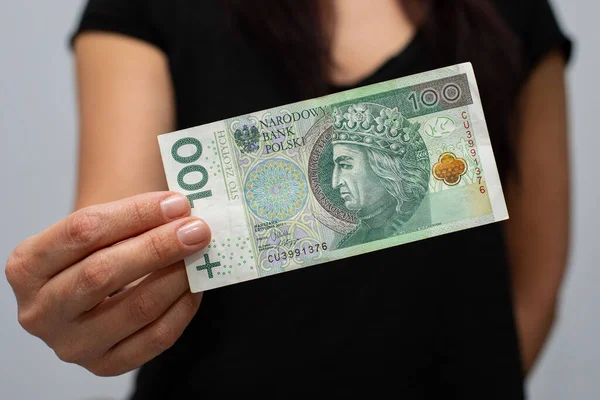 PLN 100 Polonya parası değerindeki bir banknotun kapanışı. Gri arka plandaki bir kadının elinde zloti.