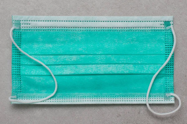 close-up of one disposable surgical masks on a wooden background