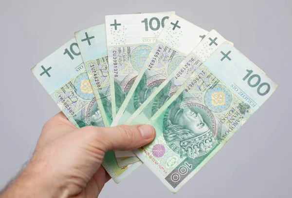 钞票的面值为100波兰兹罗提 握在一个灰色背景的妇女手里 — 图库照片