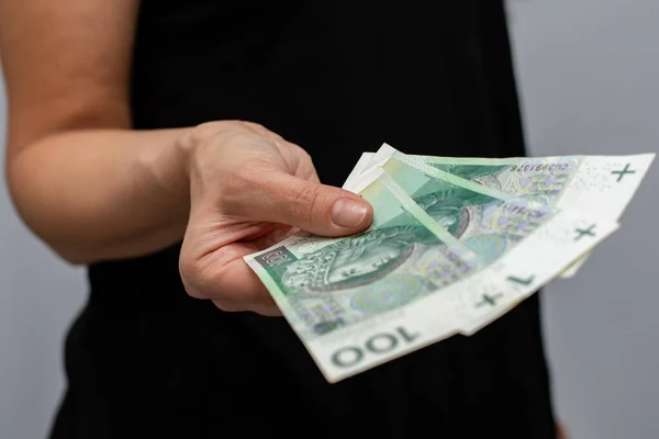 拉近一张面值100波兰兹罗提的钞票 钱的面值是100波兰兹罗提 握在一个灰色背景的妇女手里 — 图库照片