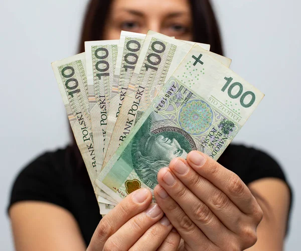 PLN 100 Polonya parası değerindeki bir banknotun kapanışı. Gri arka plandaki bir kadının elinde zloti.