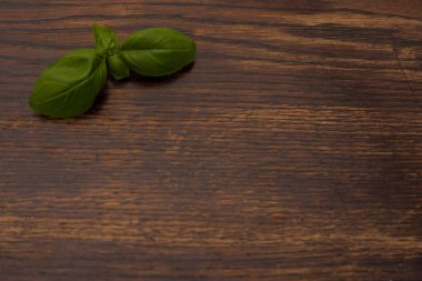 Eski ahşap arka planda taze fesleğen yaprakları ve kırmızı kiraz domatesleri yakın plan.