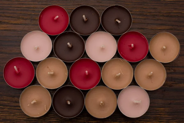 Close-up of colorful tea light candles on the background of an old wooden table