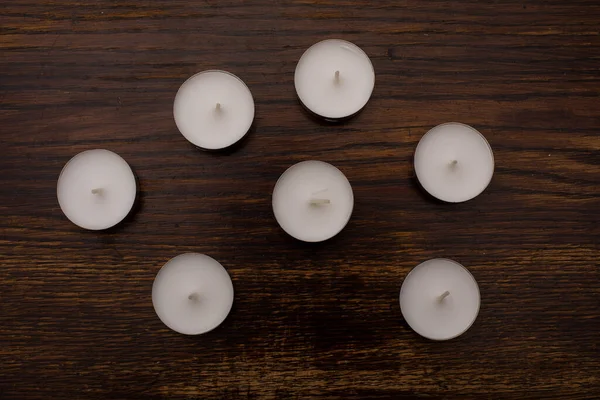 Close-up of colorful tea light candles on the background of an old wooden table
