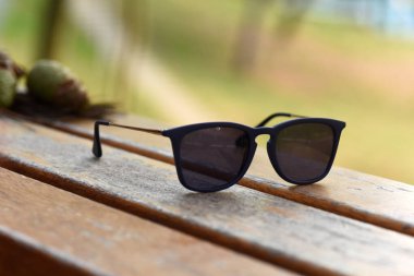 Güneş gözlüğü gözlükleri, doğal park alanında, ahşap masada.