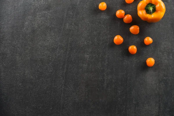 Gri taş arka planda yiyecek için sarı domates ve biber sebzeleri.
