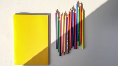 Beyaz Masadaki Renkli Kalemler ve Sarı Defter
